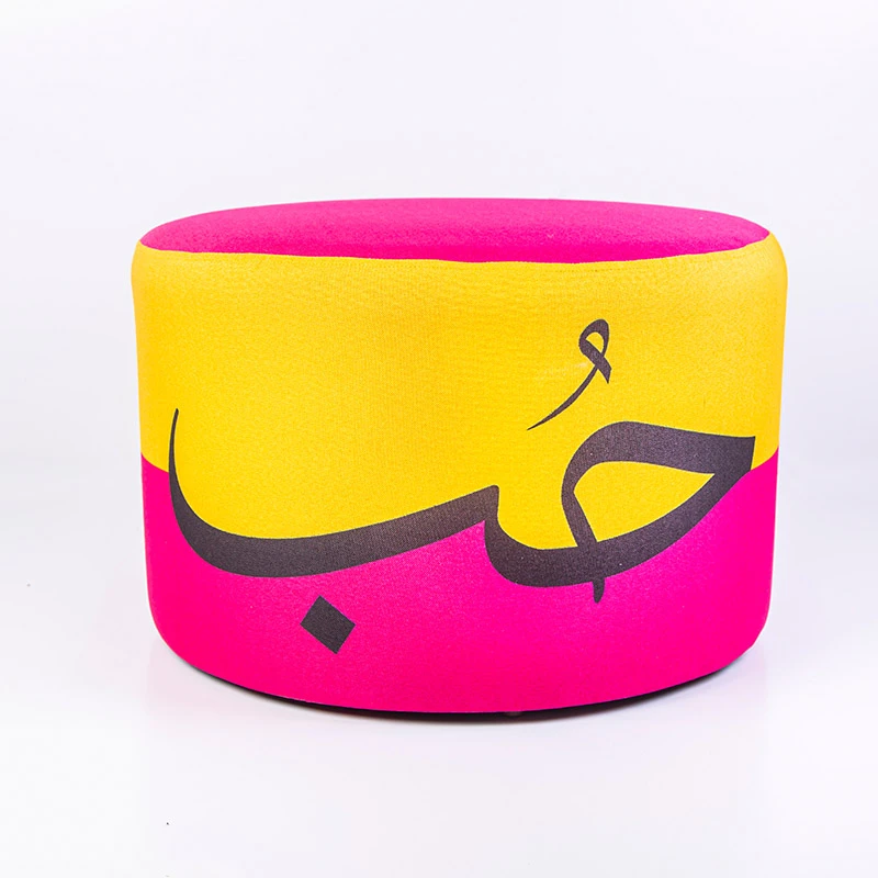 مقعد عثماني عصري مبطن يتميز بتصميم خط عربي فني نابض بالحياة "حب" - قطعة مميزة باللونين الأصفر والوردي - مؤسسة الحسين للسرطان